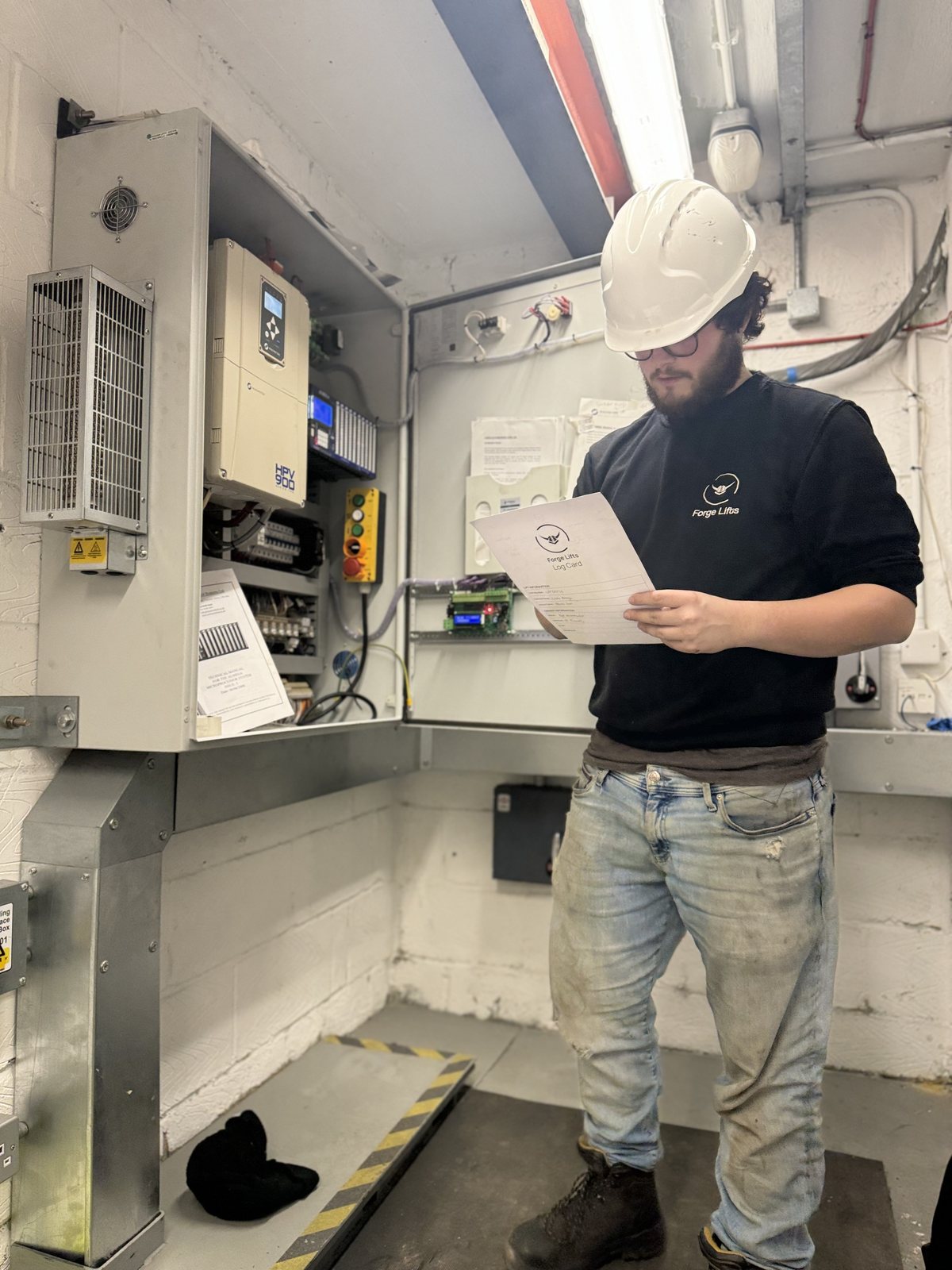 Forge Lifts engineer checking documentation in a lift machine room