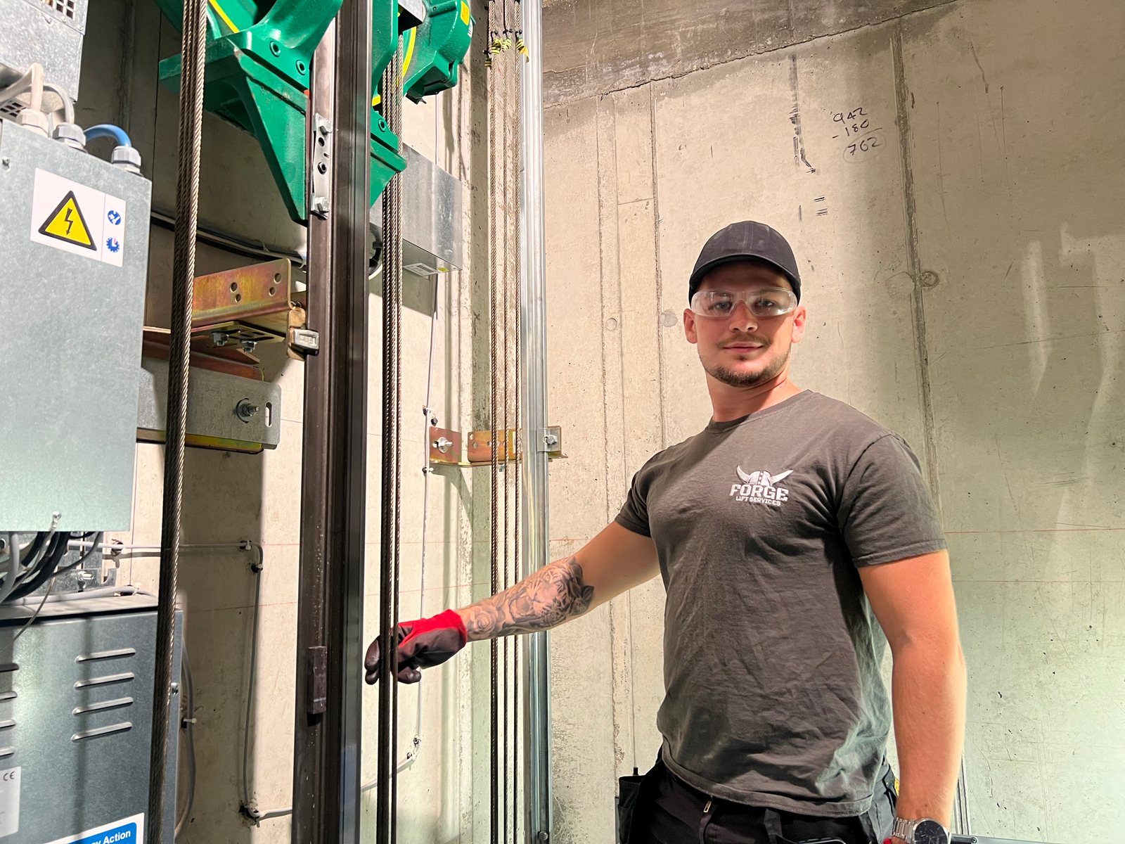 Forge Lifts engineer beside lift guide rails, ropes and installed equipment