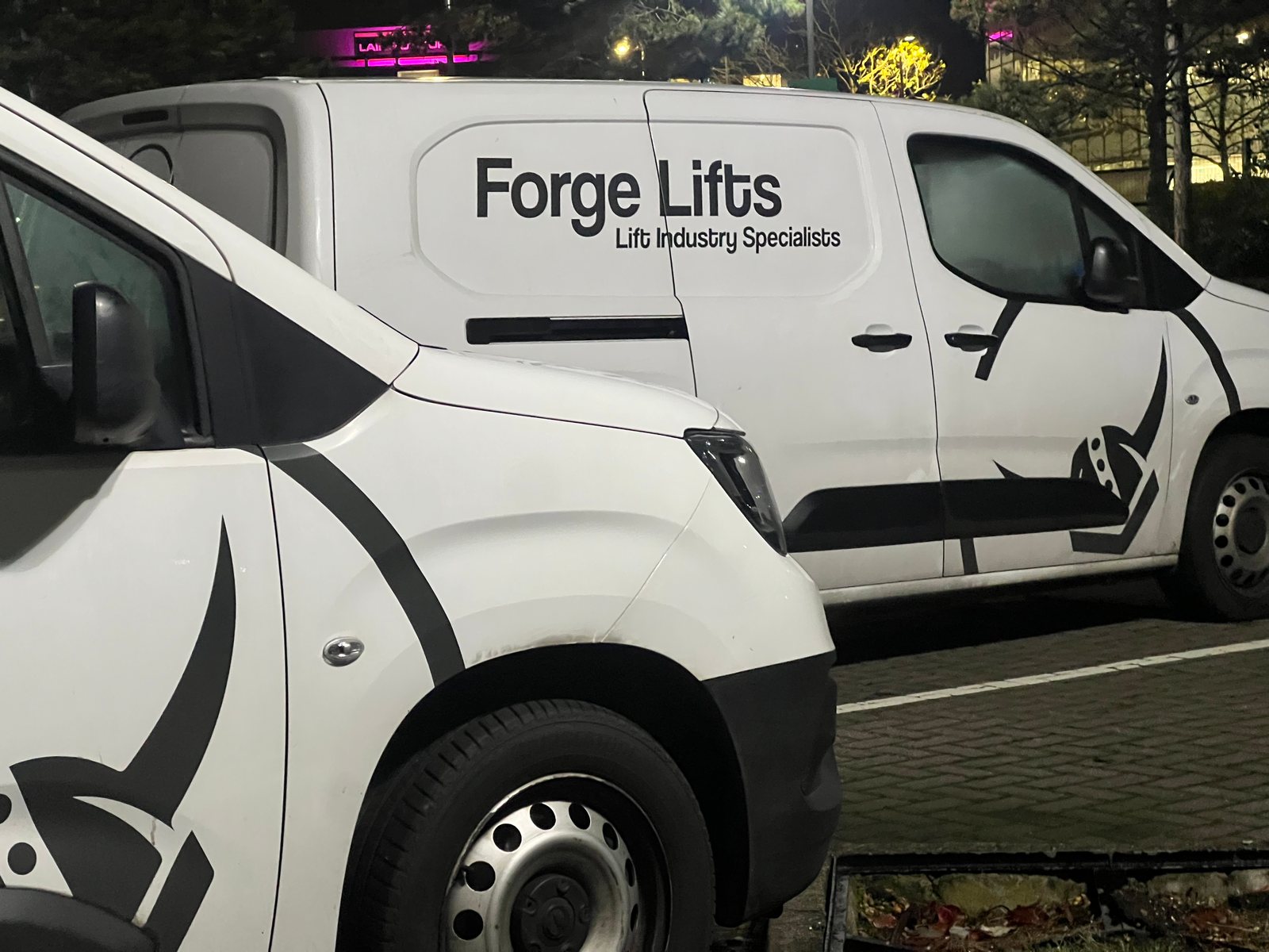 Two Forge Lifts branded service vehicles parked together